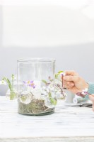 Femme plaçant des fleurs dans les petites bouteilles en verre
