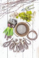 Tamis, mousse, sécateur, ficelle, plumes, boucles de brindilles de bouleau et jacinthes disposés sur une surface en bois