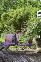 Mobilier violet sur terrasse en bois, vue sur le jardin derrière