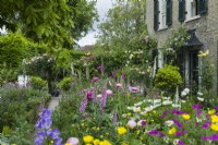 Vue sur le jardin de la ville en été avec digitales, pivoines, roses, géraniums, renoncules. Juin
