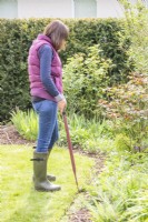 Femme utilisant des cisailles à bordure pour tailler le bord de la pelouse