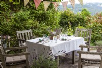 Terrasse avec ensemble table et chaises, guirlande ornée de lavande et autres fleurs - Histoire de fête d'été à la lavande