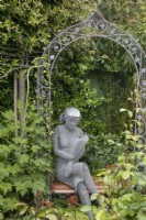 Fil sculpture d'une jeune fille lisant un livre par Derek Kinzett à Hamilton House garden en mai