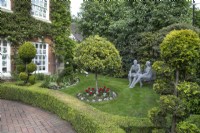 Jardin de devant avec des sculptures en fil de fer de Derek Kinzett et des arbres nuageux au jardin de Hamilton House en mai