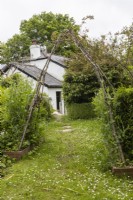 Une arche rustique menant à Lewis Cottage, jardin NGS Devon. Le printemps.