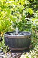 Fontaine à eau simple en ardoise dans un parterre ombragé