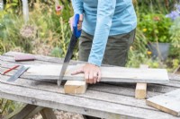 Femme sciant les planches de bois à la bonne longueur