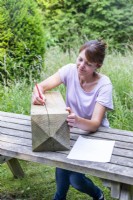 Femme copiant le dessin du papier sur la traverse en bois