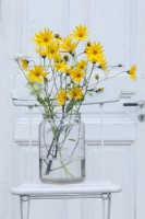 Arrangement floral avec Helianthus tuberosus contre une porte blanche à l'extérieur