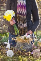 Femme créant un arrangement de Pâques en plein air avec un nid de paille et des œufs de caille.
