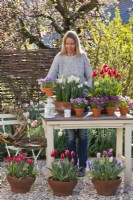 Femme organisant des fleurs de printemps sur la table.