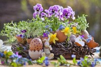 Arrangement de table de Pâques avec couronne, coquilles d'œufs plantées de cresson et de fleurs printanières.