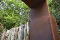 Structure de jardin en acier Corten avec clôture en bois d'eucalyptus. Été.