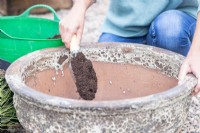 Femme remplissant un grand pot de compost