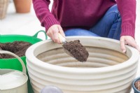 Femme remplissant le pot de compost