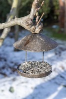 Mangeoire à oiseaux suspendue à un arbre en hiver
