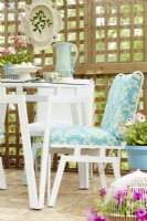 Table et chaises vintage peintes en bleu et blanc sur un patio en treillis