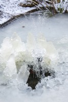Fontaine à eau dans un bassin de jardin couvert de glace