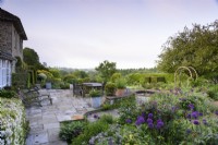Jardin de roses en terrasse formel avec beaucoup d'alliums violets en mai.