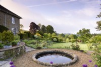 Jardin en terrasse à la française avec bassin circulaire en mai.