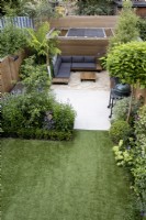 Vue en hauteur du petit jardin de banlieue avec pelouse artificielle, terrasse et pergola en bois