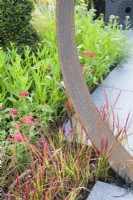 Plantation d'herbes imperata cylindrica 'Red Baron' avec détail de moongate en acier Corten - Sunburst Garden, RHS Hampton Court Palace Garden Festival 2022
