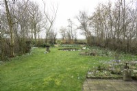 Vue d'ensemble du jardin printanier avec pelouse, bassin rond et parterres remplis de crocus et de perce-neige.