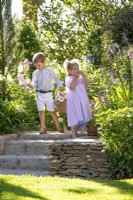 Garçon et fille cueillant des fleurs dans un jardin
