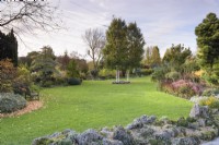 Le jardin de John Massey en octobre avec un paysage de pierre pour les alpins au premier plan et des parterres de fleurs mixtes au-delà.
