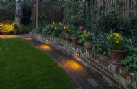 Éclairage le long d'un nouveau muret de briques dans un jardin récemment repensé.