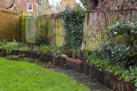 Une photo 'Avant' d'un jardin londonien en attente de relooking. Une partie du mandat consistait à remplacer les traverses de chemin de fer pourrissantes et le chemin de pierre autour du parterre de fleurs surélevé par un mur et un chemin de briques.