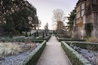 Un chemin à travers le jardin est au Bishop's Palace Garden à Wells un matin de janvier, encadré par des haies à feuilles persistantes d'Euonymus japonicus 'Green Spire'.