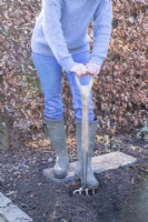 Femme utilisant une fourche pour creuser deux tranchées peu profondes