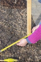 Femme mesurant la largeur de la zone pour le chemin