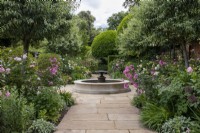 Vue sur le chemin dans le jardin sud de Morton Hall Gardens passé des parterres de roses et de plantes herbacées vers la piscine et la fontaine.