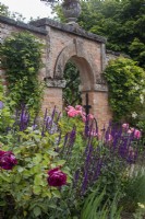 Rosa « Boscobel » et Rosa « Falstaff » avec Salvia nemorosa « Caradonna » contre l'arche de briques dans le potager de Morton Hall Gardens