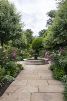 Vue sur le chemin dans le jardin sud de Morton Hall Gardens passé des parterres de roses et de plantes herbacées vers la piscine et la fontaine.