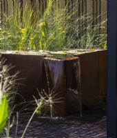 Dispositif d'eau surélevé en métal rouillé avec de l'eau tombant dans l'étang sous la grille métallique - Fenton Gardens Ltd SubAqua - BBC Gardeners' World Live 2023, Birmingham NEC - Designer Joshua Fenton