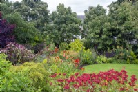 Parterre de fleurs vivaces par pelouse circulaire avec Monarda 'Gardenview Scarlet', hemerocallis, euphorbia etc. dans North House Garden