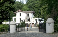 Propriétaires de la Villa Sprezzatura accueillant près du portail en fer noir et de la villa en arrière-plan.