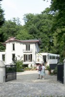 Propriétaires de la Villa Sprezzatura accueillant près du portail en fer noir et de la villa en arrière-plan.