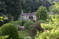 Vue sur jardin vers maison à Moor Wood, Gloucestershire, avec des roses décousues.