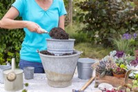 Femme remplissant des seaux de compost et les empilant pour créer un effet à plusieurs niveaux