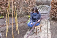 Femme utilisant du fil pour lier des brindilles de bouleau ensemble pour créer une guirlande