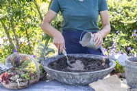 Femme mélangeant du sable avec du compost dans le pot peu profond