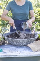 Femme mélangeant du sable avec du compost dans le pot peu profond