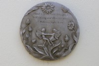 Une plaque de pierre, sur un mur crème, avec des fées dansant et des fleurs, avec une citation de A Midsummers Night Dream. Fermer.