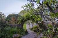 Vue à travers une arche circulaire en brique jusqu'à la maison et la pelouse à Greencombe Gardens, Devon