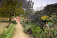 Chemin à côté du parterre de fleurs chaud dans le jardin clos de Parham House en septembre