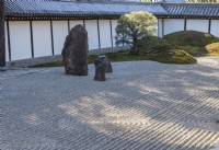 Zone de graviers ratissés avec pierres posées. Les murs environnants sont carrelés. Un seul pin japonais à côté de monticules couverts de mousse.